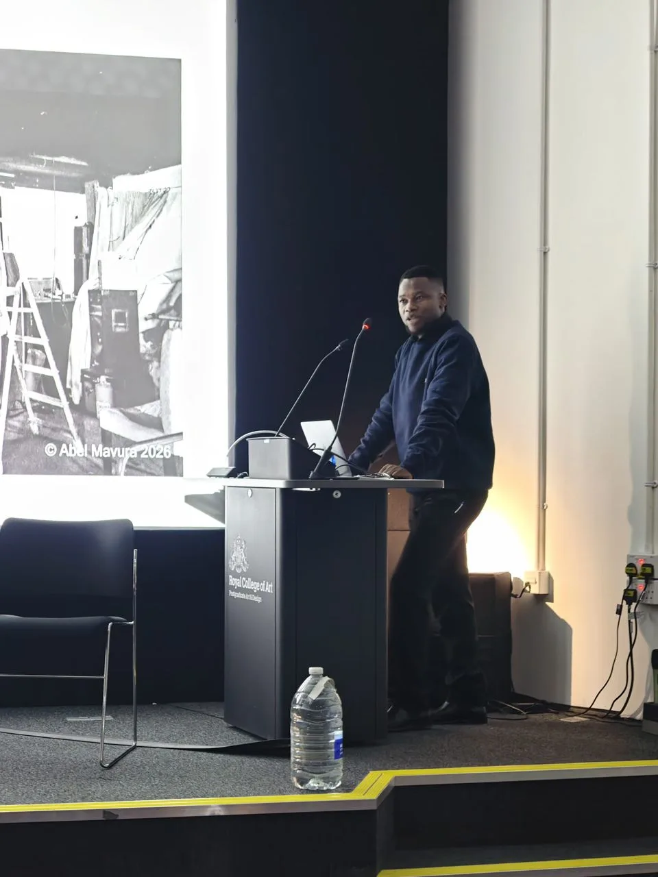 Abel Mavura presenting from the lectern to a lecture theatre audience