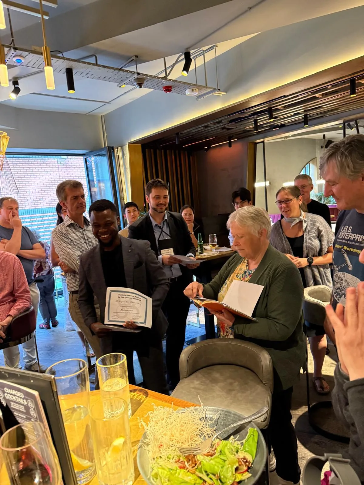Abel Mavura receiving an award certificate at an informal presentation
